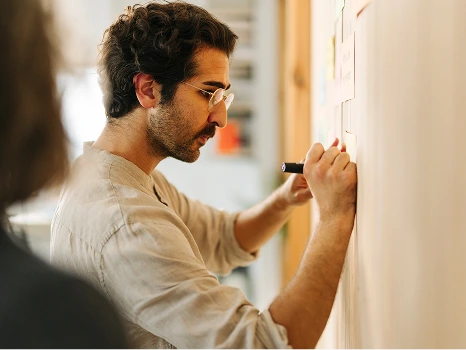 Ein Mann der etwas an ein Whiteboard schreibt